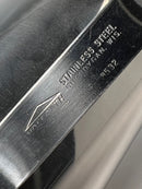 Close-up of a metal tool with branding and text on a reflective surface