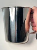 Hand holding a shiny metallic cup against a neutral background