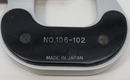 Metallic object with 'NO. 106-102' and 'MADE IN JAPAN' text on a white background